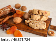 Деревянная доска с вкусным печеньем бискотти, грецкими орехами, курагой и специями на светлом фоне, крупным планом. Стоковое фото, фотограф Pixel_shot / Фотобанк Лори