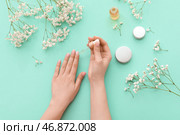 Женские руки с бутылкой масла для кутикулы, косметикой и цветами гипсофилы на цветном фоне. Стоковое фото, фотограф Pixel_shot / Фотобанк Лори