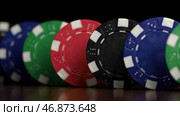 Poker chips stand in a row on a black background, a Domino effect. Стоковое фото, фотограф David Kashakhi / Фотобанк Лори