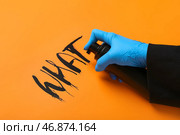Женщина в резиновой перчатке распыляет слово ЧТО на оранжевом фоне, крупным планом. Стоковое фото, фотограф Pixel_shot / Фотобанк Лори
