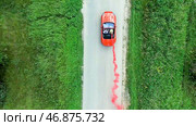 Aerial survey of red cabrioled goes on the road and couple using colored smoke.Flying over classic red convertible car traveling in the countryside at sunset with colored smoke. Стоковое фото, фотограф David Kashakhi / Фотобанк Лори