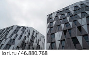 Bottom view of modern unique building with triangle shaped windows of black color on bright cloudy sky background. Стоковое фото, фотограф David Kashakhi / Фотобанк Лори