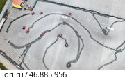 Racers traning or competing on the karting track in protective uniform and helmet, aerial view. Стоковое фото, фотограф David Kashakhi / Фотобанк Лори