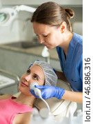 Female cosmetologist performing anti-aging face phototherapy procedure, shrink pores and repair damaged skin for young girl client in clinic of aesthetic medicine. Стоковое фото, фотограф Яков Филимонов / Фотобанк Лори