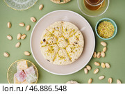 Тарелка вкусной халвы тахини с фисташками и рахат-лукумом на зеленом фоне. Стоковое фото, фотограф Pixel_shot / Фотобанк Лори