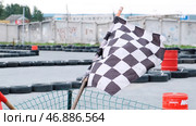 Close-up view of red and checkered start and finish flags on the outdoor karting track. Стоковое фото, фотограф David Kashakhi / Фотобанк Лори