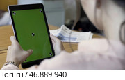 Rear view of a woman holding a tablet with chromakey with tracking marks on wooden table background. Редакционное фото, фотограф David Kashakhi / Фотобанк Лори