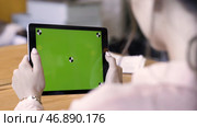 Rear view of a woman holding a tablet with chromakey with tracking marks on wooden table background. Редакционное фото, фотограф David Kashakhi / Фотобанк Лори