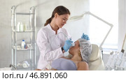 Professional female aesthetician administering hardware procedure on young woman in cosmetology clinic, using high frequency ultrasound head to open skin pores for deep penetration of nutrients. Стоковое видео, видеограф Яков Филимонов / Фотобанк Лори