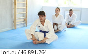 Athletes before training martial arts performs stretching butterfly pose to warm up muscles. Стоковое видео, видеограф Яков Филимонов / Фотобанк Лори