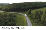 Transport, logistics concept, white truck driving on the empty road along green forest. Стоковое фото, фотограф David Kashakhi / Фотобанк Лори