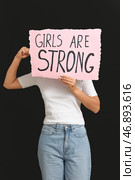 Женщина, закрывающая лицо знаком GIRLS ARE STRONG на черном фоне. Концепция феминизма. Стоковое фото, фотограф Pixel_shot / Фотобанк Лори