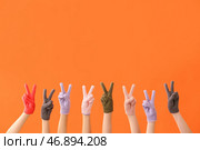 Женщины в теплых перчатках показывают победный жест на цветном фоне. Стоковое фото, фотограф Pixel_shot / Фотобанк Лори