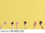 Руки, держащие ведра с попкорном и стаканы с колой на желтом фоне. Стоковое фото, фотограф Pixel_shot / Фотобанк Лори