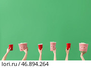 Руки, держащие ведра с попкорном и напитками на зеленом фоне. Стоковое фото, фотограф Pixel_shot / Фотобанк Лори