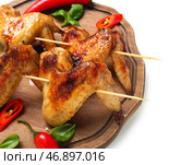 Деревянная доска с жареными куриными крылышками на белом фоне, крупным планом. Стоковое фото, фотограф Pixel_shot / Фотобанк Лори