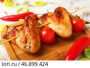Деревянная доска с жареными куриными крылышками и помидорами на светлом фоне, крупным планом. Стоковое фото, фотограф Pixel_shot / Фотобанк Лори