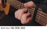 Musician playing acoustic guitar using a capo for chord variations. Стоковое видео, видеограф Дмитрий Наумов / Фотобанк Лори