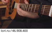Musician playing acoustic guitar using a capo for chord variations. Стоковое видео, видеограф Дмитрий Наумов / Фотобанк Лори