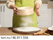 Женщина-пекарь просеивает муку на кухне. Крупный план. Стоковое фото, фотограф Pixel_shot / Фотобанк Лори
