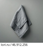 Textured gray fabric napkin hanging against a simple wall in a modern kitchen setting. Стоковое AI-изображение, AI-художник Сергей Толмачёв / Фотобанк Лори