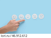 Мужчина указывает на рейтинговые смайлы на синем фоне. Концепция опроса. Стоковое фото, фотограф Pixel_shot / Фотобанк Лори