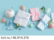 Покрашенные пасхальные яйца с подарочными коробками, ромашковыми цветами и зайцем на голубом фоне. Стоковое фото, фотограф Pixel_shot / Фотобанк Лори