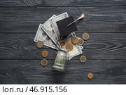 Выпускная шапочка с деньгами на темном деревянном фоне. Концепция студенческого займа. Стоковое фото, фотограф Pixel_shot / Фотобанк Лори