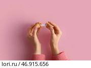 Женские руки с разломанным печеньем с предсказанием на розовом фоне. Стоковое фото, фотограф Pixel_shot / Фотобанк Лори