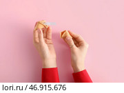 Женские руки с разломанным печеньем с предсказанием на розовом фоне. Стоковое фото, фотограф Pixel_shot / Фотобанк Лори