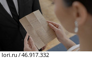 View over the shoulder of a young caucasian woman in front of her unrecognizable groom and pronouncing wedding vow. Стоковое фото, фотограф David Kashakhi / Фотобанк Лори