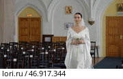 Young caucasian woman walking along empty rows of a chapel. Стоковое фото, фотограф David Kashakhi / Фотобанк Лори