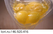 Raw eggs with yolks and proteins spread from plastic container for baking. Стоковое фото, фотограф David Kashakhi / Фотобанк Лори