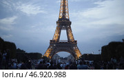 Many tourists sit on lawn and enjoy beautiful view of shining Eiffel tower in evening in summer. Стоковое фото, фотограф David Kashakhi / Фотобанк Лори
