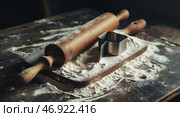 Rolling pin and cookie cutter on floured wooden surface in a cozy kitchen early in the morning. Стоковое AI-изображение, AI-художник Сергей Толмачёв / Фотобанк Лори