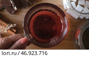 Cup of freshly brewed fruit tea, pouring hot water from the kettle into a glass cup on wooden background. Стоковое фото, фотограф David Kashakhi / Фотобанк Лори
