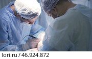 Two professional surgeons make incisions to patient under anesthesia. Стоковое фото, фотограф David Kashakhi / Фотобанк Лори
