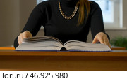 Woman sitting at the table leafing through the book. Стоковое фото, фотограф David Kashakhi / Фотобанк Лори