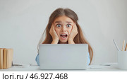 Surprised young girl expressing shock while using a laptop at home. Молодая девушка с длинными волосами демонстрирует шокированное выражение лица, сидя за столом, закрыв лицо руками и держа перед собой ноутбук. Скорее всего, она реагирует на что-то неожиданное на экране. Стоковое AI-изображение, AI-художник Katsiaryna Repich / Фотобанк Лори