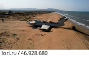 Aerial view of a ruined abandoned airplane found in an uninhabited island near the sea on blue sky background. Стоковое фото, фотограф David Kashakhi / Фотобанк Лори