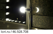 Close up of moths and flies fly near the lamp on a building wall at night. Стоковое фото, фотограф David Kashakhi / Фотобанк Лори