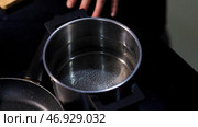 Top view of transparent water getting hotter inside a pot on a black stove surface background. Стоковая иллюстрация, иллюстратор David Kashakhi / Фотобанк Лори