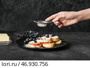 Женщина посыпает сахарной пудрой вкусные сырники на тарелке. Стоковое фото, фотограф Pixel_shot / Фотобанк Лори