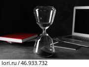 Стильные песочные часы и ноутбук на темном столе в офисе. Концепция дедлайна. Стоковое фото, фотограф Pixel_shot / Фотобанк Лори