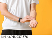 Спортивный бегун проверяет пульс на цветном фоне. Стоковое фото, фотограф Pixel_shot / Фотобанк Лори
