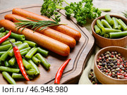 Доска с вкусными сосисками, стручковой фасолью и перцем чили на деревянном фоне, крупным планом. Стоковое фото, фотограф Pixel_shot / Фотобанк Лори