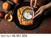 Женщина посыпает сахарной пудрой вкусную персиковую галету на гранж-фоне. Стоковое фото, фотограф Pixel_shot / Фотобанк Лори