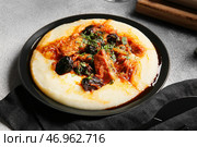 Тарелка с вкусным картофельным пюре, соусом и тушеной говядиной с черносливом на сером столе. Стоковое фото, фотограф Pixel_shot / Фотобанк Лори