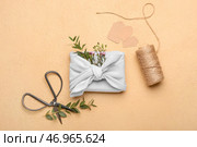 Композиция с подарочной коробкой, обернутой тканью, веревкой, бирками и ножницами на цветном фоне. Стоковое фото, фотограф Pixel_shot / Фотобанк Лори