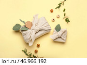 Подарочные коробки, обернутые тканью, деревянными бусинами и цветочным декором на цветном фоне. Стоковое фото, фотограф Pixel_shot / Фотобанк Лори